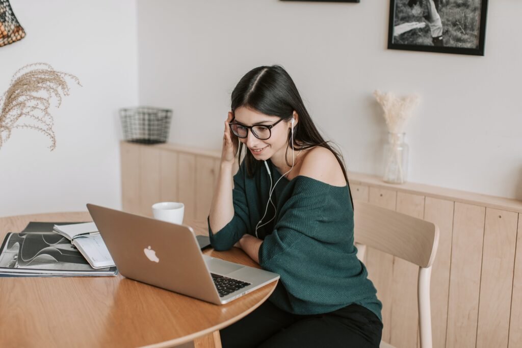 A focused young woman participates in certified online courses, representing the future of education. She's studying on her laptop in a well-lit room that combines comfort and modern design, highlighting the shift towards digital learning environments.