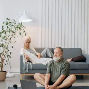 Senior man and woman practicing mindfulness meditation in a modern living room.
