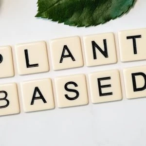 Tiles spelling out "PLANT BASED" with green leaves in the background.