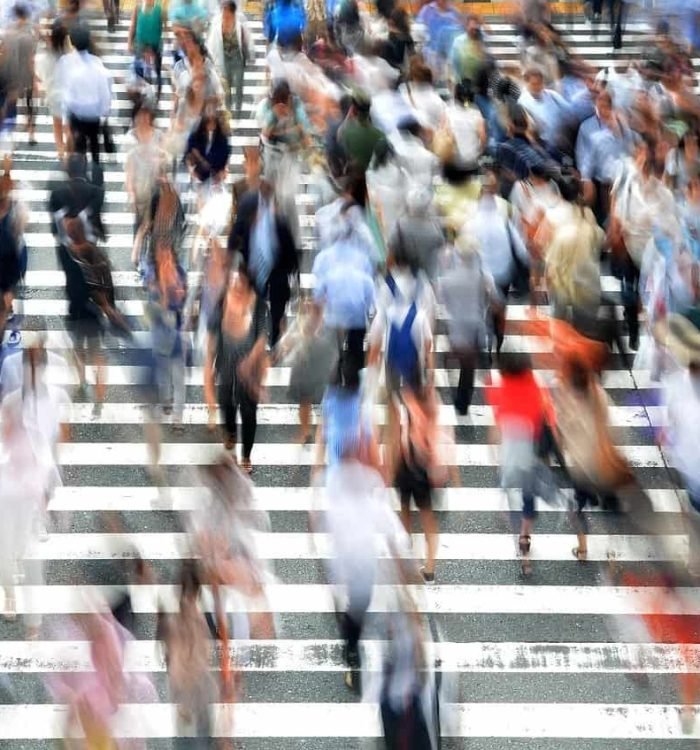 Crowded city crosswalk with numerous pedestrians crossing in different directions.