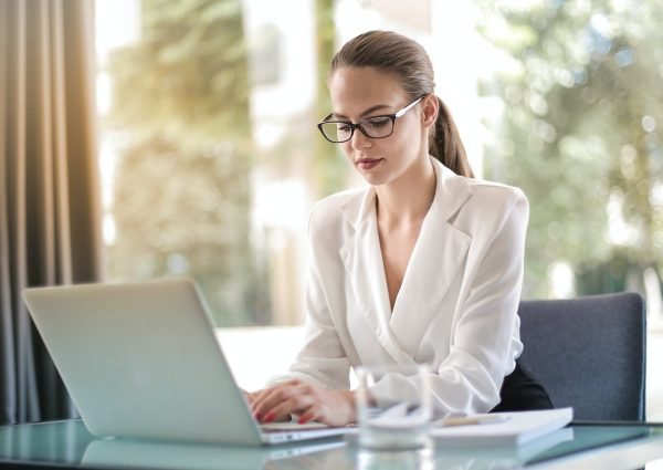 concentrated female entrepreneur typing on laptop in workplace